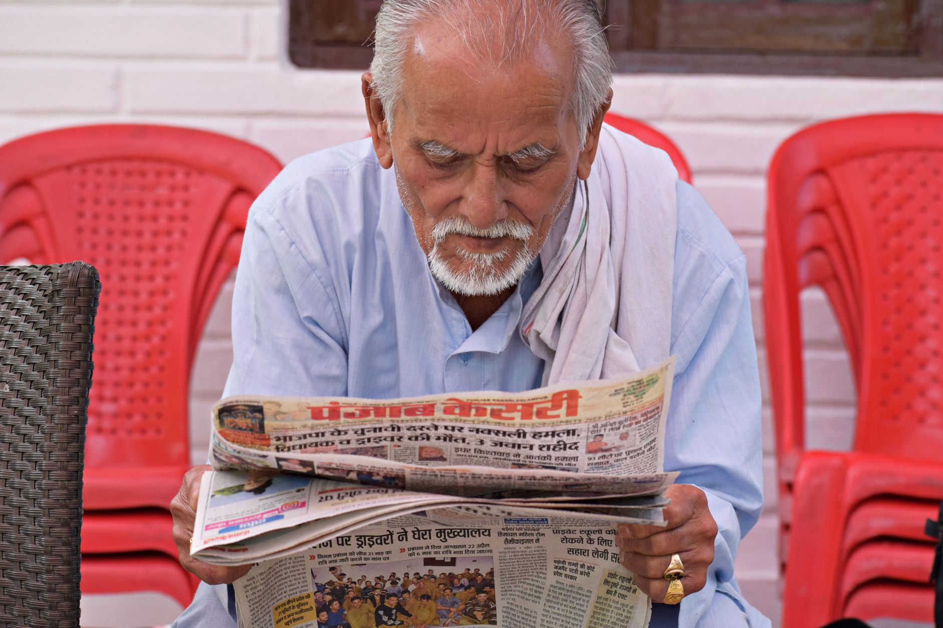 Elderly man engaging in daily reading of a newspaper while seated outdoors. — Die aufregendsten Jackpot-Spiele bei Ocean Bree