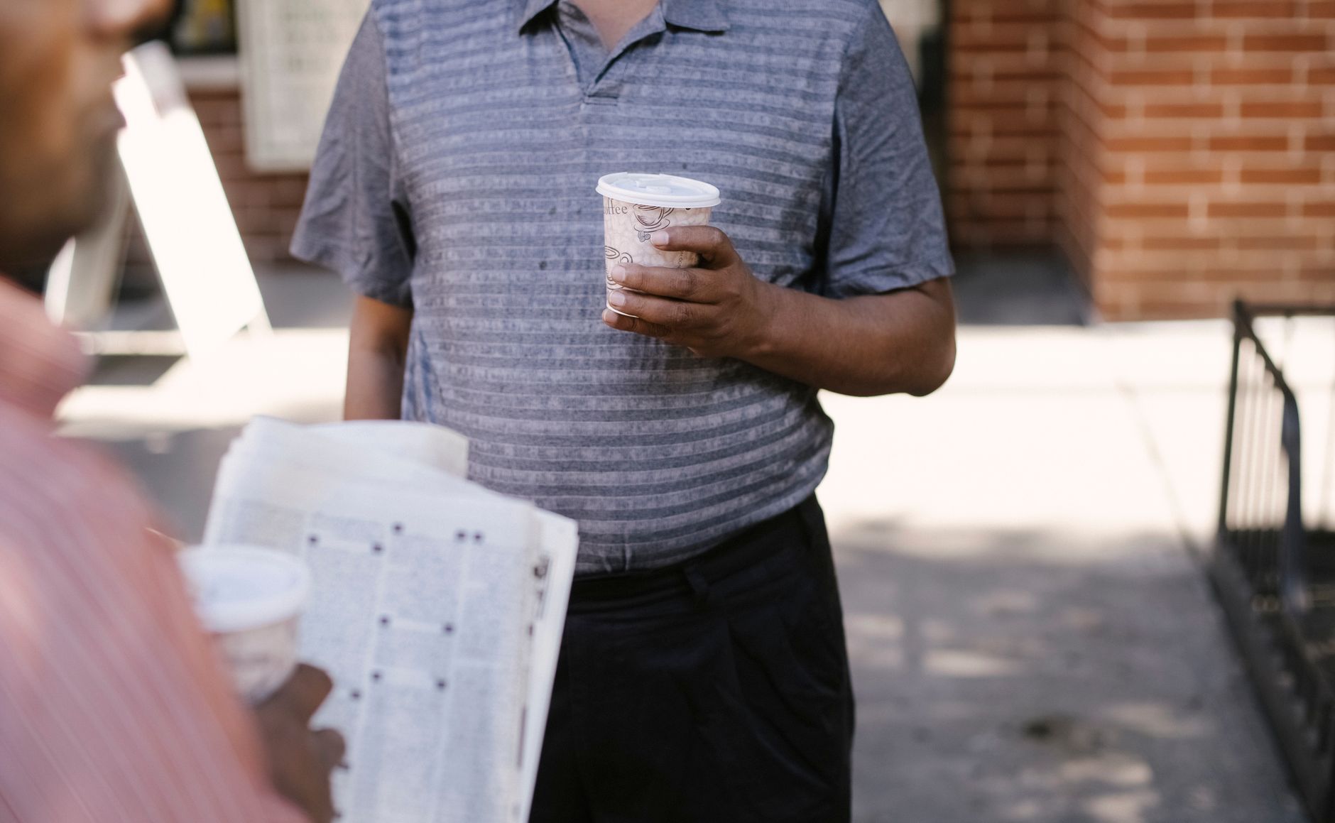 Crop anonymous ethnic male friends with coffee to go and newspaper speaking on city pavement — Erfahrungen von Spielern im Sp