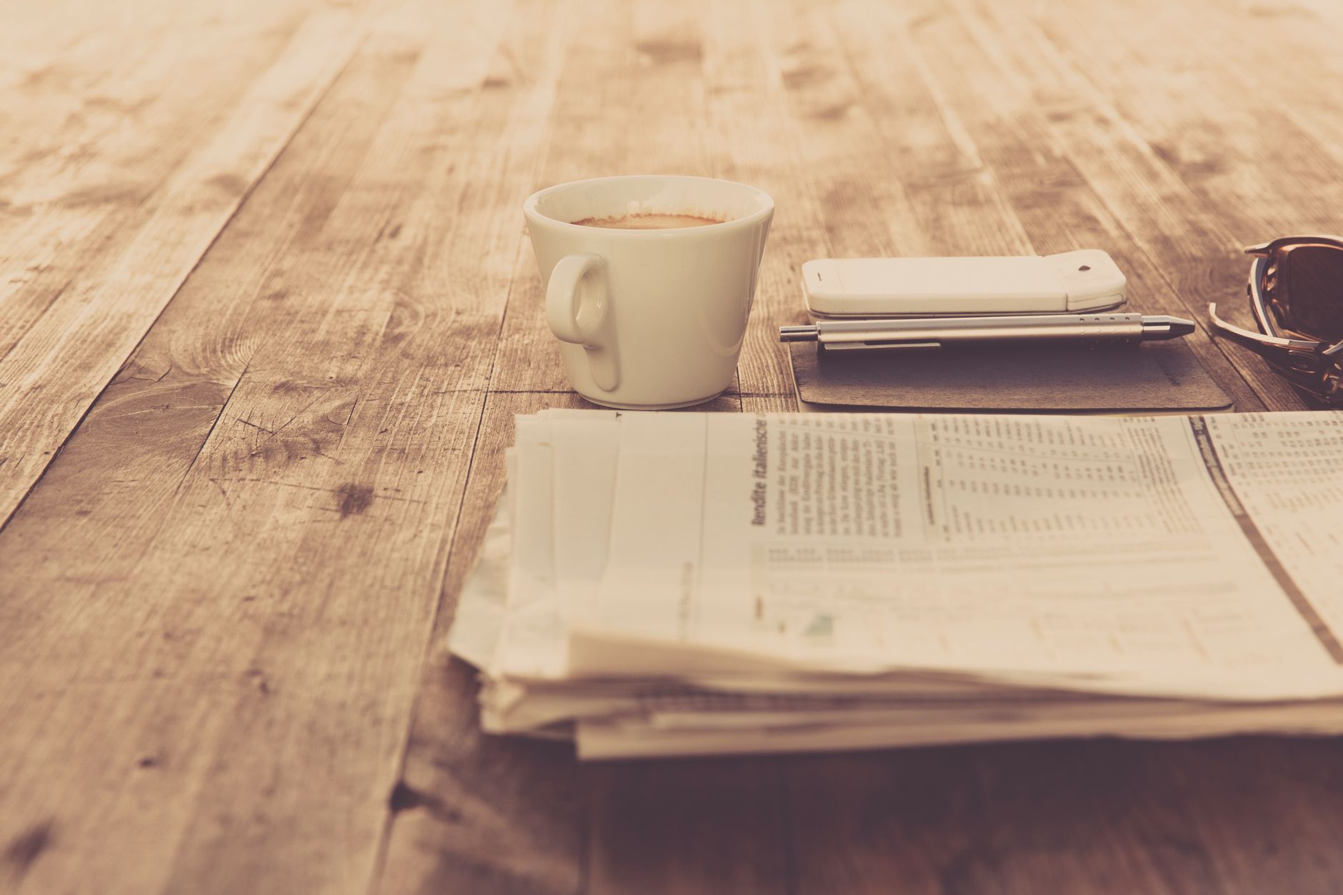 A warm vintage morning setup with coffee, newspaper, and smartphone on wooden table. — Mafia Casino: Vincite Veloci per il Gi